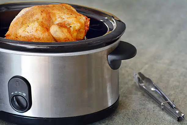 Roasted Chicken cooked in a slow cooker on kitchen bench. copy space