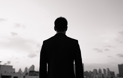 Businessman standing on a roof and looking at city.