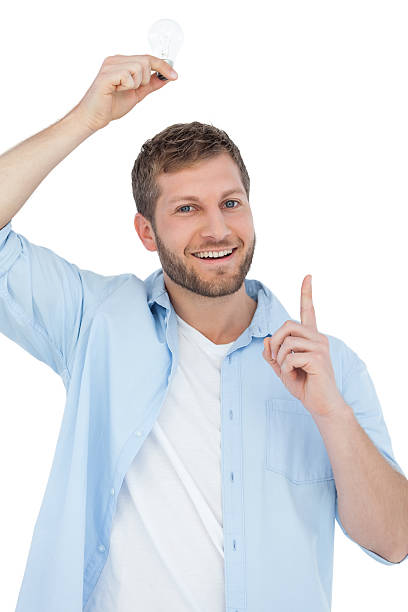 Smiling model holding a bulb above his head Smiling model holding a bulb above his head on white background man with a light bulb over his head stock pictures, royalty-free photos & images