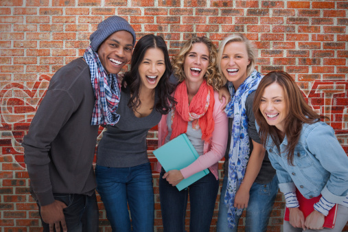 Smiling group of friends posing together on brick background