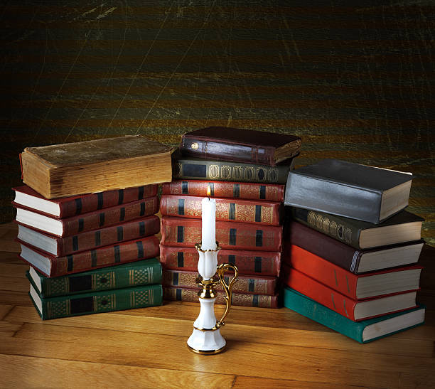 istock Old stack of books with candlestick and burning candle 494297793