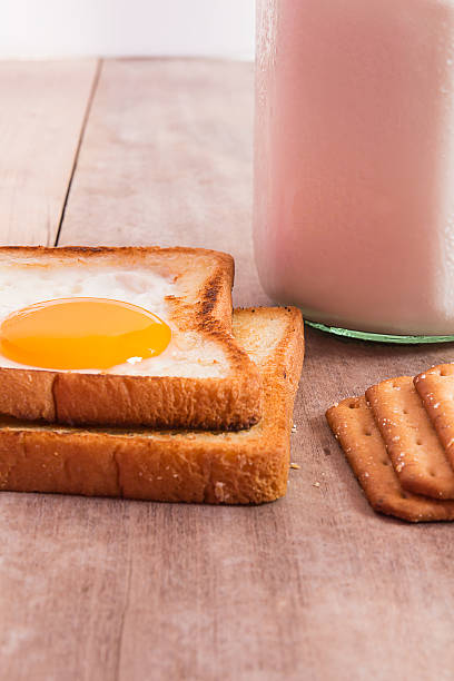 desayuno con huevos fritos, toasts, leche en mesa de madera. - texas tea fotografías e imágenes de stock