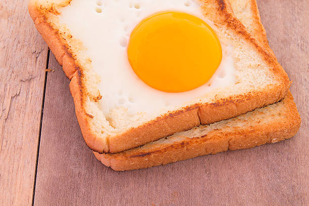 breakfast with fried eggs, toasts on wooden table.