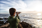 Woman with spyglass looking toward ocean