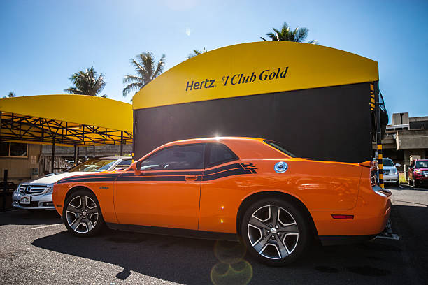 orange dodge challenger garé près du bureau de location de voitures hertz - the hertz corporation photos et images de collection