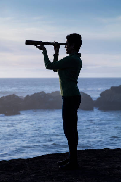 istock Woman with spyglass looking toward ocean 494308822