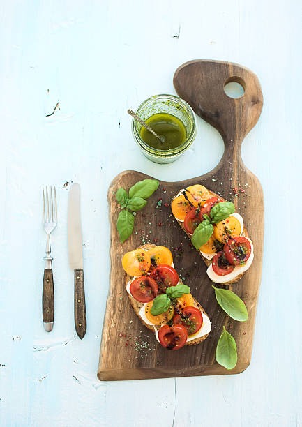 istock Tomato, mozzarella and basil sandwiches on dark wooden chopping board 494308834