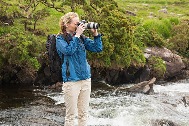 istock Blonde standing on rock in a stream taking photo 494310325