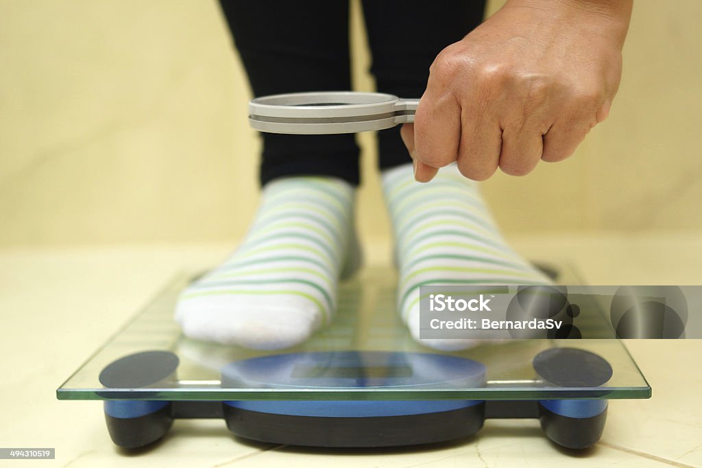 woman feet on weighing scales looking weight over magnifying Weight Stock Photo