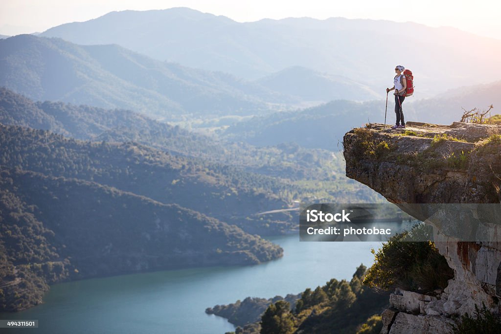 Female hiker standing on cliff Female hiker standing on cliff and enjoying valley view Mountain Stock Photo