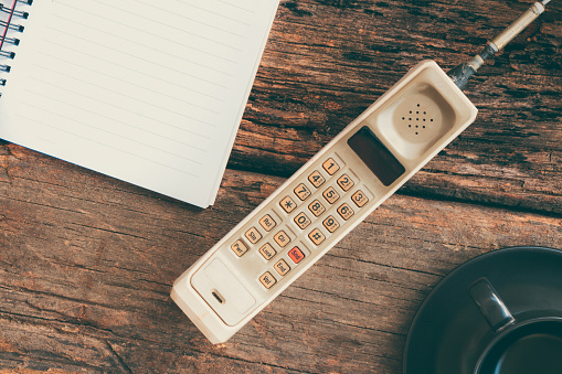 vintage mobile phone with blank paper note and cup of coffee (vintage style)