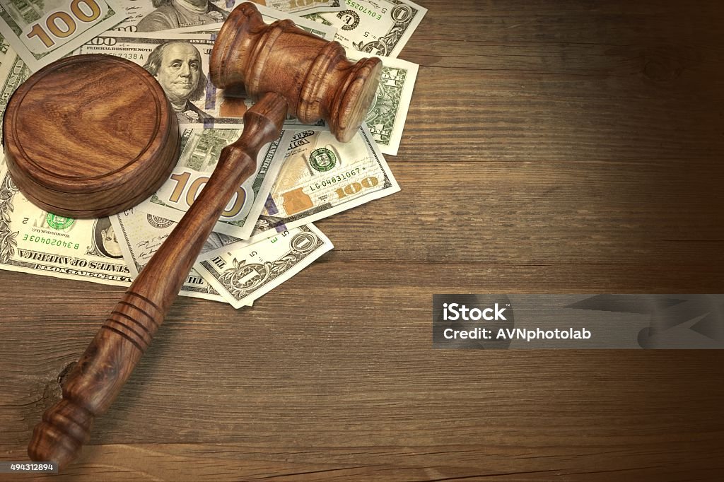 Judges or Auctioneer Gavel And Money On The Wooden Table Concept For Corruption, Bankruptcy Court, Bail, Crime, Bribing, Fraud, Auction Bidding. Judges or Auctioneer Gavel, Soundboard And Bundle Of Dollar Cash On The Rough Wooden Textured Table Background. Fee Stock Photo