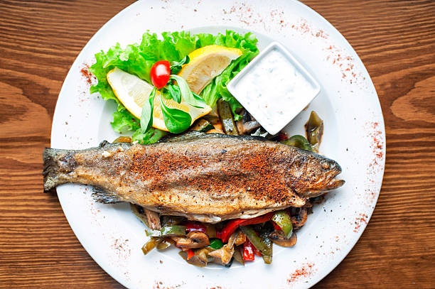 istock Grilled trout with fried vegetables and lemon. Main course. 494313997
