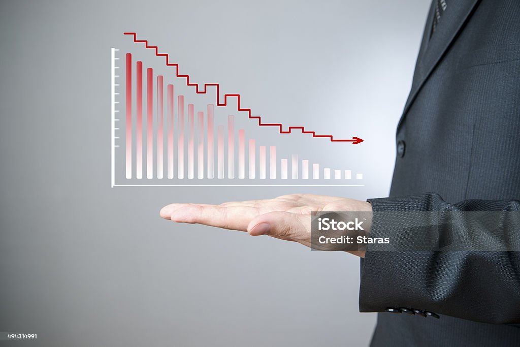 Businessman presenting a sustainable decrease development Business concept. Businessman presenting a sustainable decrease development on a bar chart on gray background. Deterioration Stock Photo