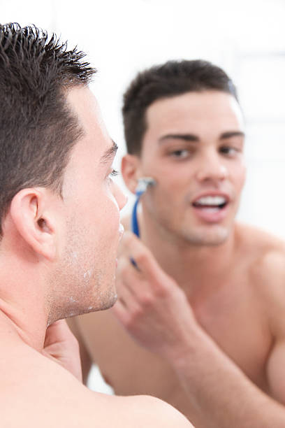 istock attractive man shaving in front of bathroom mirror 494315467