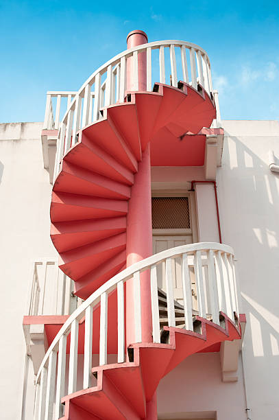 istock Red spiral staircase against white wall 494316152