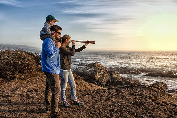 rodzina z spyglass patrząc w stronę oceanu - hand held telescope zdjęcia i obrazy z banku zdjęć
