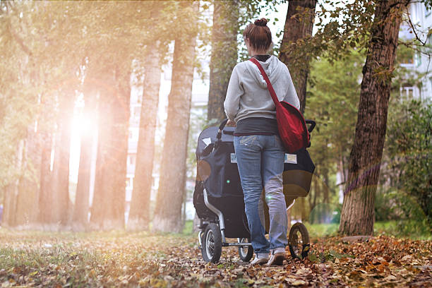 istock Mom with stroller walks in autumn park alley 494318424