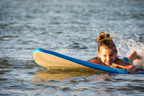 Little girl splashing around on surfboard