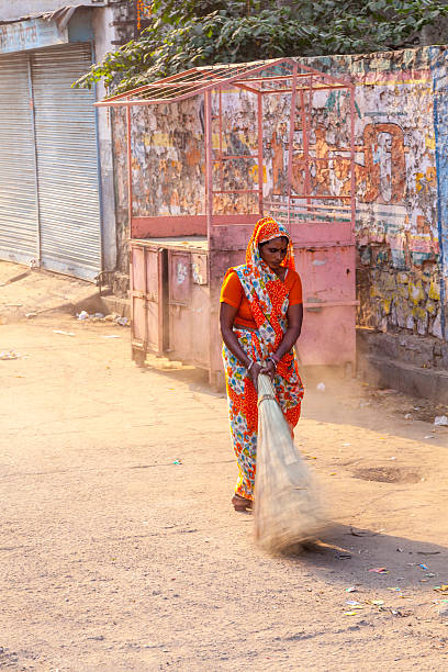 woman of fourt class in brightly colored clothing Jaipur, India - October 20, 2012: woman of fourt class in brightly colored clothing cleans the street in Jaipur, India. They earn 300 IRP for two hours paid by the government. rag picker stock pictures, royalty-free photos & images