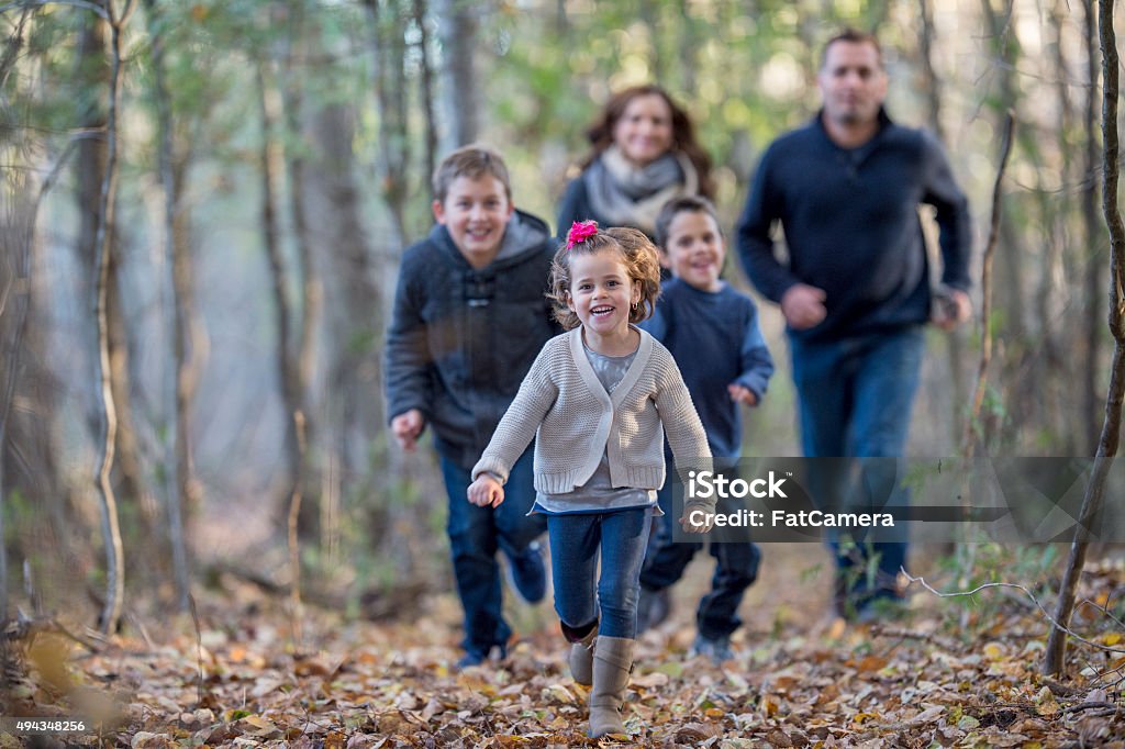 Family Playing Tag in the Woods A family is playing tag and is chasing each other through the woods on a beautiful fall day. 2015 Stock Photo