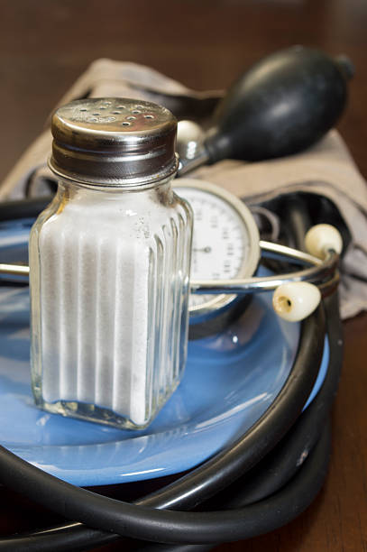 salt  and blood pressure gauge salt shaker and blood pressure gauge on plate sodium intake stock pictures, royalty-free photos & images