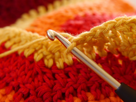 Attractive senior woman doing crocheting, making a hand-made jute basket.