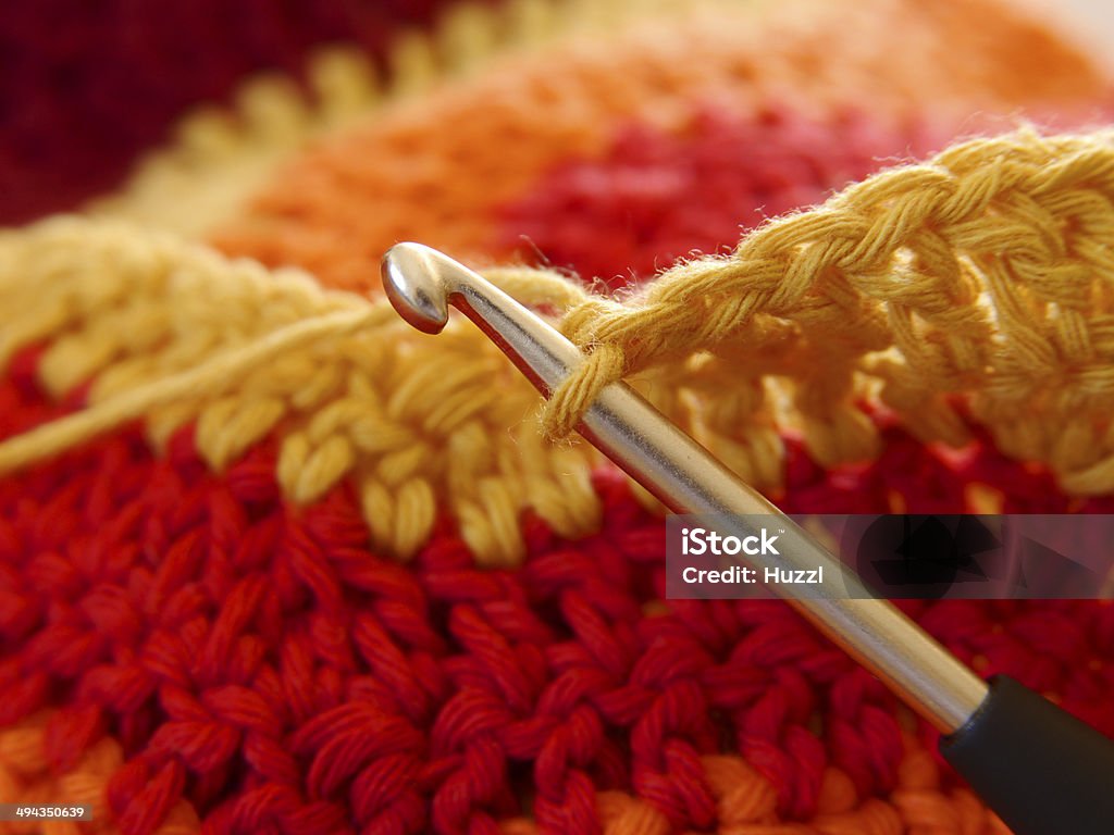 Crochet neck in colorful wool A half-ceiling. Close-up of a crochet hook with wool in various warm shades of red. Crochet Stock Photo