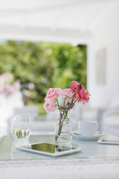 istock Pink roses on patio table next to coffee cup and digital tablet 494358239