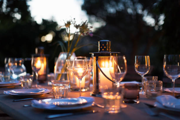 istock Candles in lanterns on patio dining table with place settings 494358579