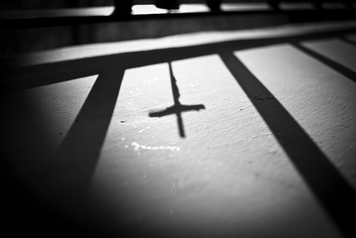 This is a Christian cross shadow with a very contrasting light over a rough surface 