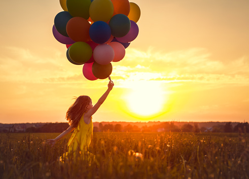 Little girl with balloons on the Sunset