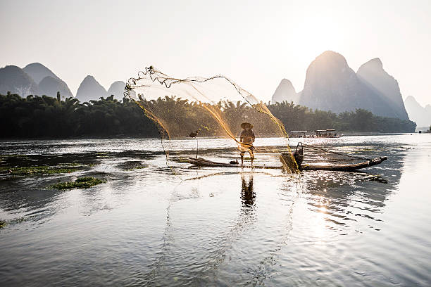 istock cormorant fisherman throwing a net 494387566