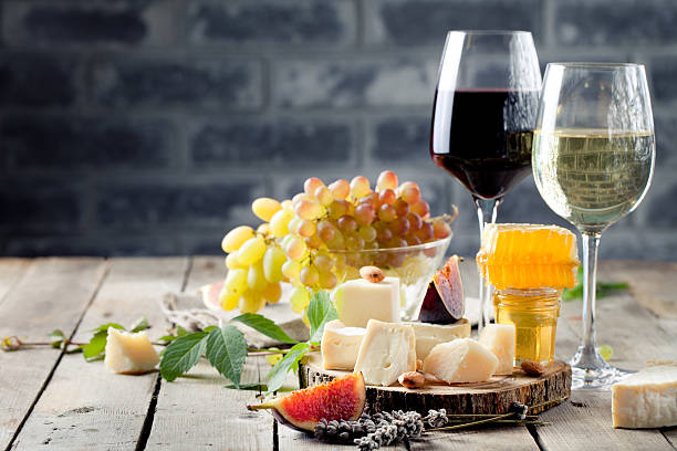 Grape, cheese, figs and honey with a glasses wine. Grape, cheese, figs and honey with a glasses of red and white wine on a stone and wood background cheese wine food appetizer stock pictures, royalty-free photos & images