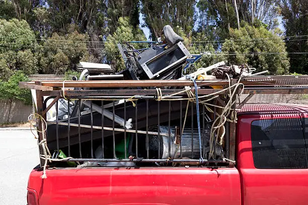 Back of red pickup truck filled with junk. Horizontal.