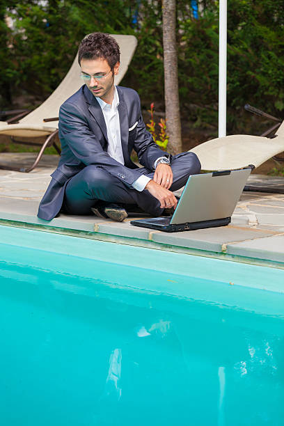 istock Young Businessman with Computer next to Swimming Pool 494397101