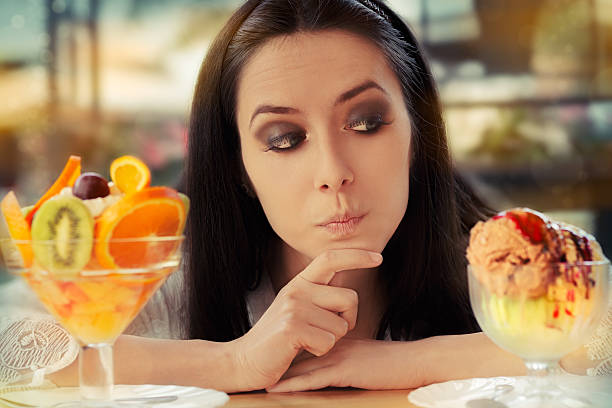 istock Young Woman Choosing Between Fruit Salad and Ice Cream Desserts 494397689