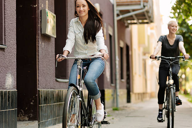 istock Smiling young women riding bicycles together 494398135