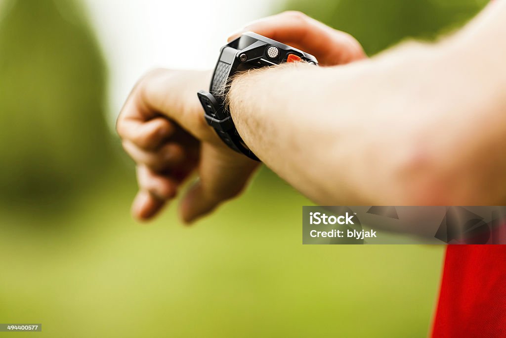 Croce paese sentiero runner guardando orologio sportivo - Foto stock royalty-free di Adulto