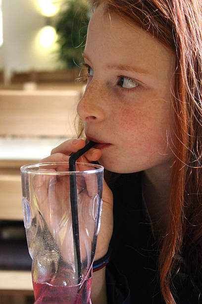 istock Image of young girl drinking blackcurrant fruit drink with straw 494400819