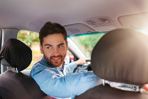 Handsome young man in a blue shirt driving a car