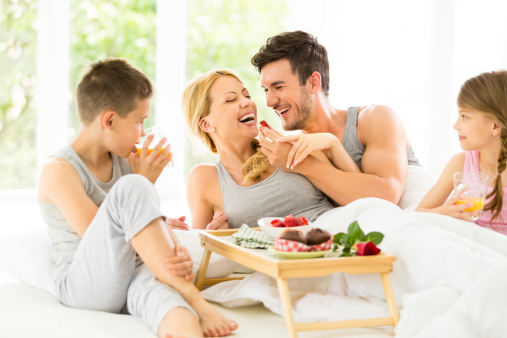 Young family having breakfast in bed.