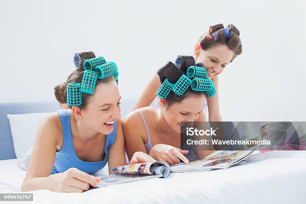 Girls Wearing Pajamas And Hair Rollers Reading Magazines Stock Photo - Download Image Now