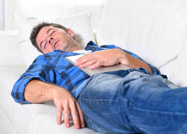 istock man sleeping on couch relaxing after working with digital tablet 494416326
