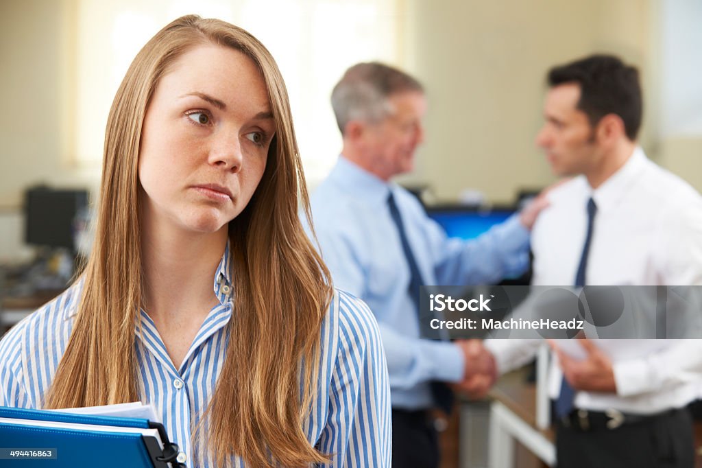 Unhappy Businesswoman With Male Colleague Being Congratulated Passed over for promotion Sex Discrimination Stock Photo