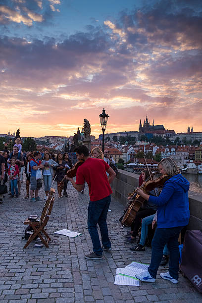 Prague, Сzech Republic - August 22, 2015: A group of street musicians play music at the Charles Bridge, with the Castle of Prague on the background.