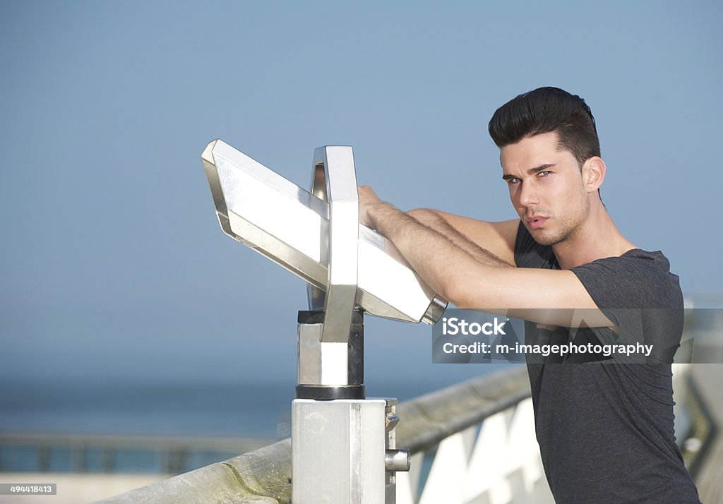 Attractive man leaning on telescope on tourism pier Portrait of an attractive man leaning on telescope on tourism pier 20-24 Years Stock Photo