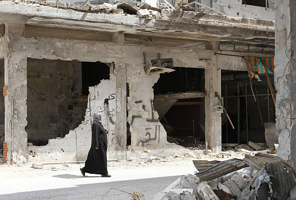 kobieta spaceruje w pobliżu zniszczone domy w homs - muslim terrorist zdjęcia i obrazy z banku zdjęć