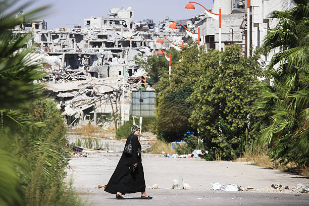 Woman goes near the area destroyed by the fighting Homs, Syria - September 22, 2013: A woman walks near a residential area in the city of Homs destroyed in the fighting between the rebels of the Syrian National Army syria stock pictures, royalty-free photos & images