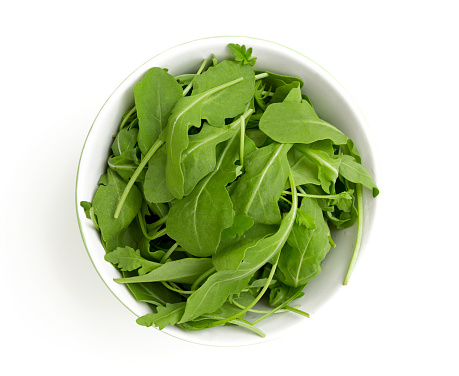 rucola in a glass bowl isolated on white background